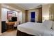 Well-lit bedroom features neutral decor, a workspace, and curtains that frame the beautiful city lights at night at 125 E Harmon Ave # 3406 & 3408, Las Vegas, NV 89109