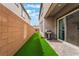 A cozy outdoor space with artificial grass, stone patio, grill, and sliding glass door access into the home at 1364 Cerulean Ave, Henderson, NV 89002