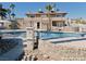 Backyard pool featuring a stone surround and view of a two-story home with second story balcony at 1828 Casa Vista Dr, Las Vegas, NV 89146