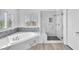 Bright renovated bathroom with marble tiling, soaking tub, and glass enclosed shower at 2566 Antique Blossom Ave, Henderson, NV 89052