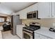 Well-lit kitchen featuring stainless steel appliances, white cabinets, and an open flow to the living space at 280 Pear Meadow St, Henderson, NV 89012