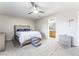Bedroom with carpet flooring featuring a king bed, grey decor, ceiling fan and a peek of the bathroom at 3221 Yolanda Ln, Las Vegas, NV 89121