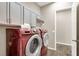 Modern laundry room with red washer and dryer, overhead cabinets, and a convenient folding counter for laundry tasks at 7420 Zonal Ave, Las Vegas, NV 89131