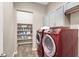 Well-organized laundry room with red washer and dryer units, gray cabinets, and open shelving for storage at 7420 Zonal Ave, Las Vegas, NV 89131