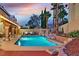 Backyard pool with a wooden deck and rock details at sunset at 9225 Evergreen Canyon Dr, Las Vegas, NV 89134