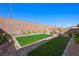 Spacious backyard featuring low-maintenance artificial grass, rock accents, and a privacy wall at 984 Brilliant Meadow Ave, North Las Vegas, NV 89086