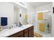 A bathroom with a double vanity, two mirrors, a walk-in shower, and yellow accent towels at 984 Brilliant Meadow Ave, North Las Vegas, NV 89086