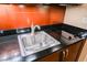 Efficient kitchenette featuring a stainless steel sink, black countertop, and wood cabinets at 145 E Harmon Ave # 2503, Las Vegas, NV 89109