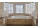 A soaking tub surrounded by block windows and decorative tiling at 1901 Rosemere Ct, Las Vegas, NV 89117