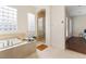 Bright bathroom featuring a soaking tub, glass block window, and a glass door shower at 7307 Iron Oak Ave, Las Vegas, NV 89113