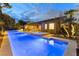 Stunning backyard pool and spa area with covered patio and outdoor seating at twilight at 7307 Iron Oak Ave, Las Vegas, NV 89113