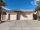 Tan home showcasing a two-car garage, desert landscaping, and a red tile roof, all under a bright blue sky at 8350 Campana Dr, Las Vegas, NV 89147