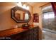 Vanity area features a uniquely patterned sink, framed mirror, custom lighting and wood cabinet at 8880 W La Mancha Ave, Las Vegas, NV 89149