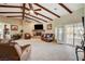 Living room featuring beamed vaulted ceiling, tile flooring, stone fireplace, and patio doors at 8880 W La Mancha Ave, Las Vegas, NV 89149