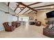 Spacious living room featuring beamed vaulted ceiling, tile flooring, and stone fireplace at 8880 W La Mancha Ave, Las Vegas, NV 89149