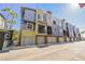 A street view showcases modern townhomes with garages, balconies, and colorful exteriors, complemented by palm trees at 9050 W Tropicana Ave # 1178, Las Vegas, NV 89147