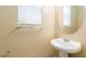 Half bath featuring a pedestal sink, round mirror, modern fixtures and a window with privacy blinds at 9445 Sweetwood Ave, Las Vegas, NV 89149