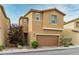 Two-story home with a two-car garage, tan stucco exterior, and green landscaping in front at 9445 Sweetwood Ave, Las Vegas, NV 89149