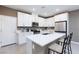Modern kitchen with stainless steel appliances, white cabinets, island with seating, and quartz countertops at 11439 Peak Landing Ave, Las Vegas, NV 89138