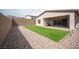 Side view of backyard featuring artificial grass, and rock landscaping leading to covered patio at 11701 Hatchling Ave, Las Vegas, NV 89138