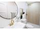 Modern bathroom with a round mirror, gold fixtures, and tiled shower at 119 Cedar St, Henderson, NV 89015