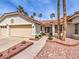 Charming home featuring a two-car garage, desert landscaping, and mature palm trees at 1276 Spanish Armada Rd, Las Vegas, NV 89123