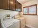 The laundry room has wood cabinets above the washer and dryer and a shuttered window for natural light at 1276 Spanish Armada Rd, Las Vegas, NV 89123