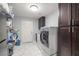 Well-equipped laundry room with modern washer, dryer, storage, and stylish tile flooring at 1550 Tiptop Trl, Pahrump, NV 89048