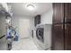 Functional laundry room with modern washer and dryer, storage cabinets and tile floors at 1550 Tiptop Trl, Pahrump, NV 89048