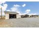 View of property with multiple outbuildings including open garages, under a bright, partly cloudy sky at 1550 Tiptop Trl, Pahrump, NV 89048