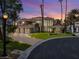 Stunning two-story home with lush landscaping, large windows, and a circular driveway at dusk at 42 Sawgrass Ct, Las Vegas, NV 89113