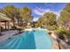 Backyard pool with water feature and stairs, surrounded by palm trees and desert landscaping at 52 Via Paradiso St, Henderson, NV 89011