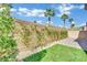 Desert landscaping with a brick wall, artificial turf, and lush green foliage at 6945 Trevelez St, Las Vegas, NV 89149