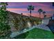 Well-lit backyard featuring a brick wall, artificial turf, and desert foliage at dusk at 6945 Trevelez St, Las Vegas, NV 89149
