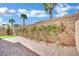 Stone-paved backyard with grass, desert vegetation, and a tall brick wall at 6945 Trevelez St, Las Vegas, NV 89149