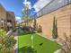 Picturesque backyard with a putting green, mature trees, and retaining wall, creating a tranquil outdoor setting at 72 Reverie Heights Ave, Henderson, NV 89011