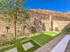 Inviting backyard with a putting green, retaining wall, and trees, perfect for outdoor recreation and relaxation at 72 Reverie Heights Ave, Henderson, NV 89011