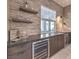 Attractive wet bar featuring stacked stone backsplash, floating shelves, and a built-in wine refrigerator at 72 Reverie Heights Ave, Henderson, NV 89011