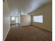 Cozy carpeted living room with a large window, vaulted ceiling, and an opening leading to a room with wood flooring at 8009 Draco Cir # 201, Las Vegas, NV 89128
