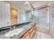 Bathroom featuring dual sinks, granite counters, and a glass-enclosed shower and tub at 11593 Glowing Sunset Ln, Las Vegas, NV 89135