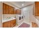 Well-equipped laundry room with wood cabinets, a sink, and a modern washer and dryer at 11593 Glowing Sunset Ln, Las Vegas, NV 89135