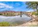 Scenic pond view with rocky waterfall, lush landscaping, and distant mountain backdrop at 11593 Glowing Sunset Ln, Las Vegas, NV 89135