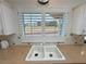 The kitchen sink has white cabinets, granite countertops, tiled backsplash, and a window with shutters with a view of the outdoors at 1211 Bourbon St, Pahrump, NV 89048