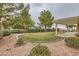 Landscaped backyard with a covered patio, a circular lawn, and mature trees and shrubbery at 2385 Orangeburg Pl, Henderson, NV 89044