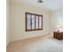 Bright, carpeted bedroom featuring a window with brown shutters, a lamp, and a wooden nightstand at 2385 Orangeburg Pl, Henderson, NV 89044