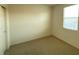 A simple bedroom with beige walls and carpet, featuring a window and closet at 5183 Silica Chalk Ave, Las Vegas, NV 89115