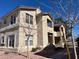 Beige stucco two-story home with a red tiled roof and landscaped front yard, set against a blue sky at 520 Arrowhead Trl # 1411, Henderson, NV 89015
