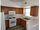 Well-lit kitchen with white appliances, wood cabinets, and a window providing natural light at 520 Arrowhead Trl # 1411, Henderson, NV 89015