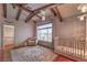 Bedroom with exposed beams, brick accent wall, and neutral furnishings; crib and ample natural light at 8953 Belconte Ln, Henderson, NV 89074