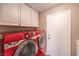 Modern laundry room equipped with a red washer and dryer, along with white storage cabinets at 8953 Belconte Ln, Henderson, NV 89074